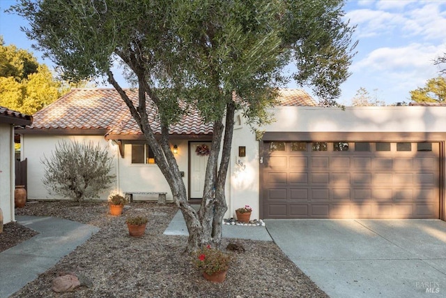 view of front of property featuring driveway, an attached garage, a tile roof, and stucco siding