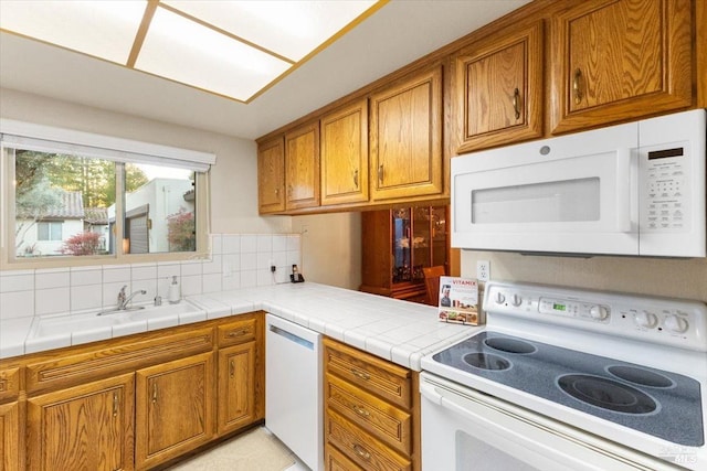 kitchen featuring decorative backsplash, white appliances, tile counters, and sink