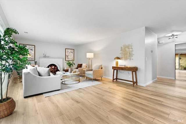 living room with light wood finished floors, a fireplace, and baseboards