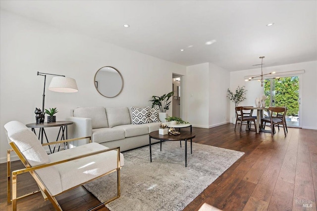 living room with dark wood-type flooring and a notable chandelier