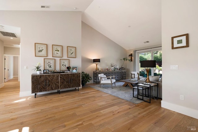 living area featuring wood-type flooring, baseboards, visible vents, and high vaulted ceiling