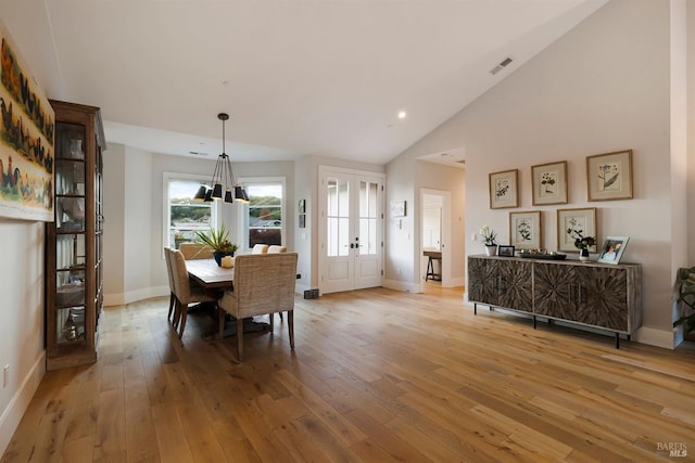 dining space with french doors, light wood finished floors, visible vents, and baseboards
