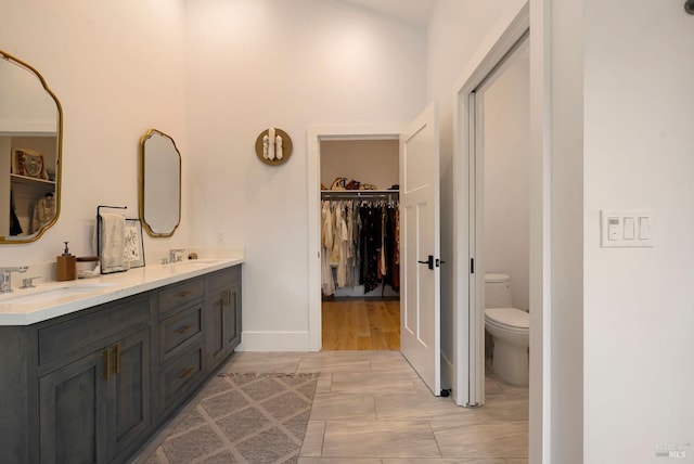 full bath with a spacious closet, a sink, double vanity, and toilet