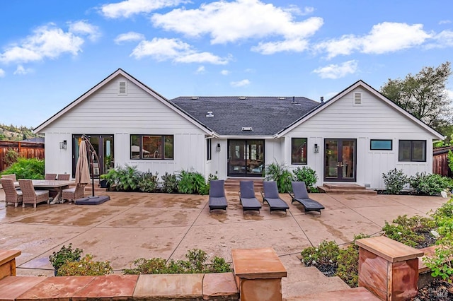 rear view of house featuring board and batten siding, french doors, fence, a patio, and entry steps