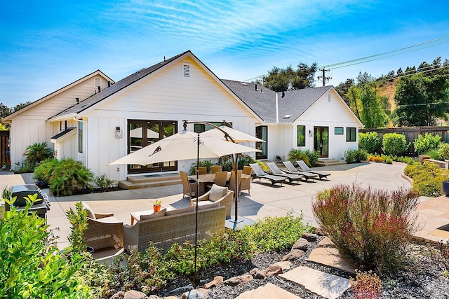 rear view of house featuring fence, outdoor lounge area, a patio area, entry steps, and board and batten siding