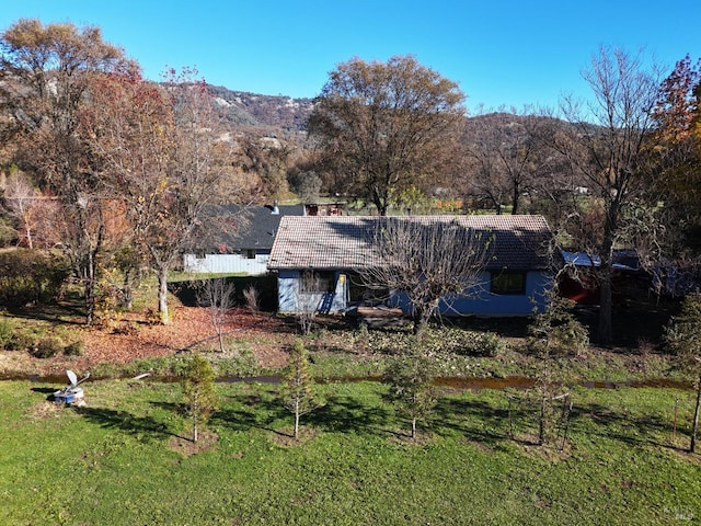 back of property featuring a mountain view and a yard