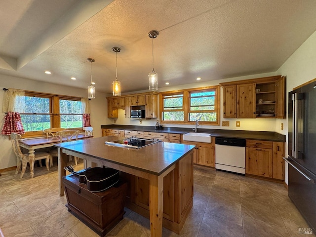 kitchen with a wealth of natural light, decorative light fixtures, sink, a center island, and black appliances