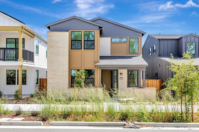 contemporary home with fence, stone siding, and stucco siding