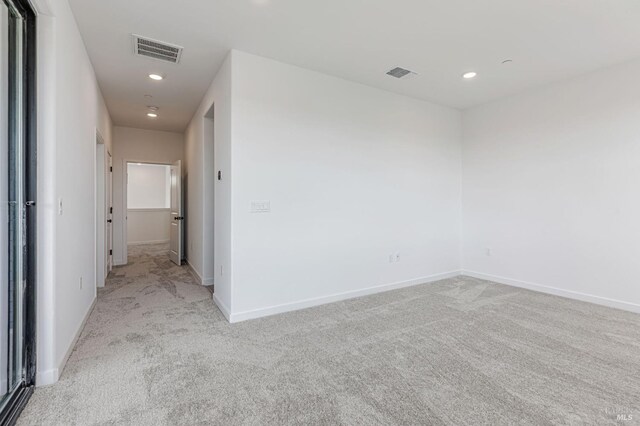empty room with recessed lighting, baseboards, visible vents, and light carpet