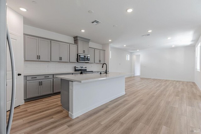 kitchen featuring gray cabinetry, appliances with stainless steel finishes, a sink, and visible vents