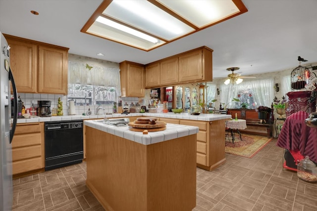 kitchen with tile counters, a center island, black dishwasher, and tasteful backsplash