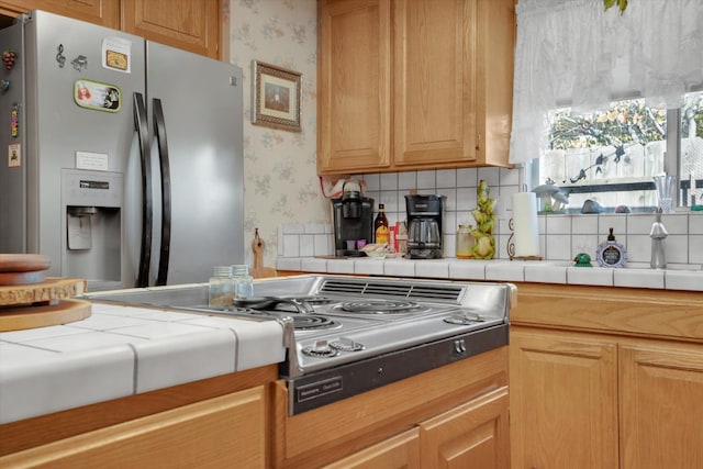 kitchen featuring tile countertops, wallpapered walls, and appliances with stainless steel finishes