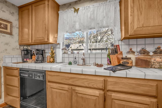 kitchen with dishwasher, tile countertops, backsplash, and wallpapered walls