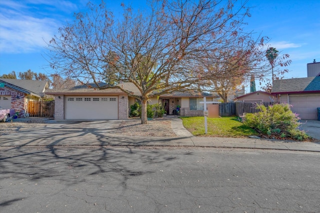 view of front of home featuring driveway, brick siding, an attached garage, and fence