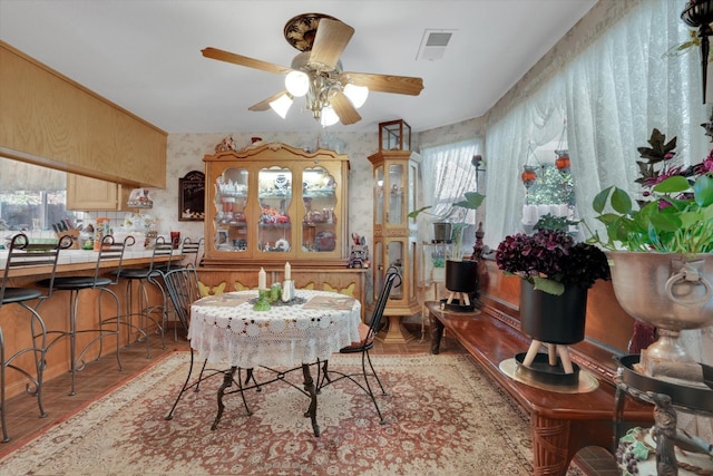 dining room featuring visible vents, ceiling fan, and wallpapered walls