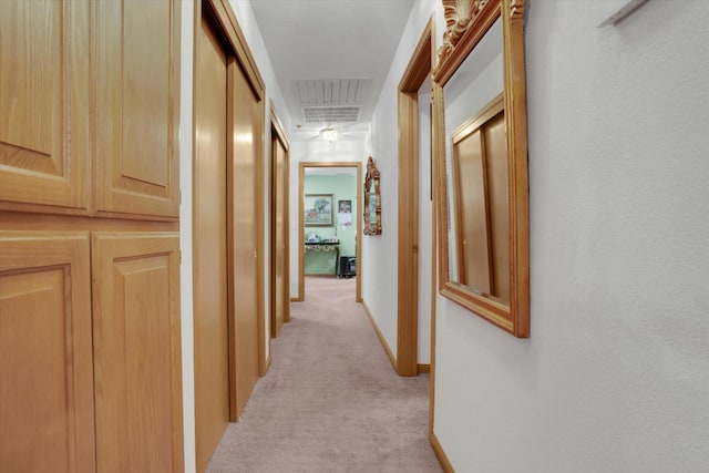 hallway featuring light colored carpet, visible vents, and baseboards