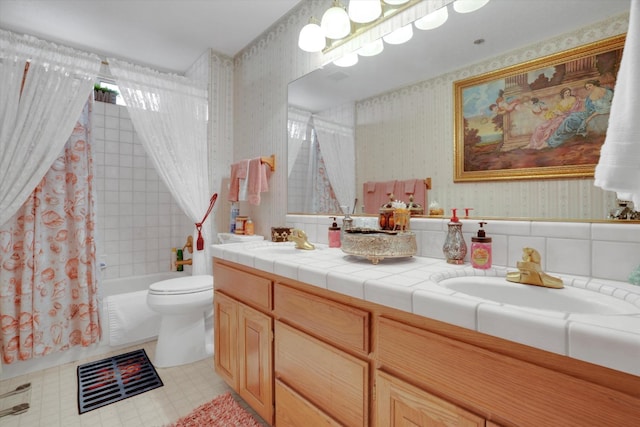 bathroom with double vanity, a sink, toilet, and wallpapered walls