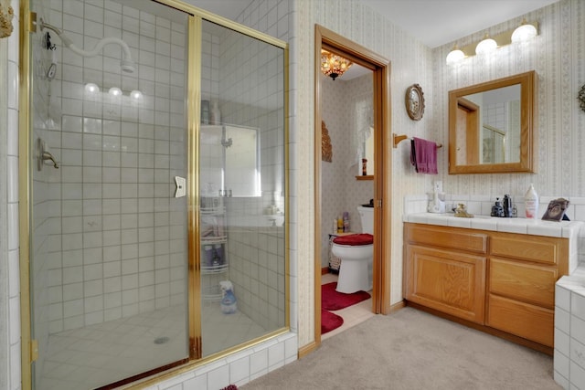 bathroom featuring toilet, wallpapered walls, vanity, and a stall shower