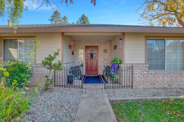 entrance to property with brick siding and a porch