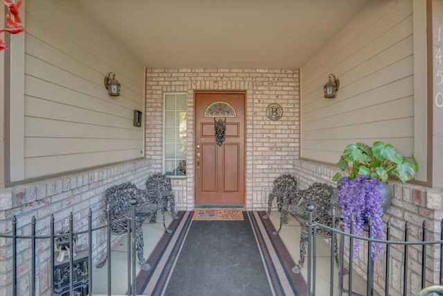 property entrance with a porch and brick siding