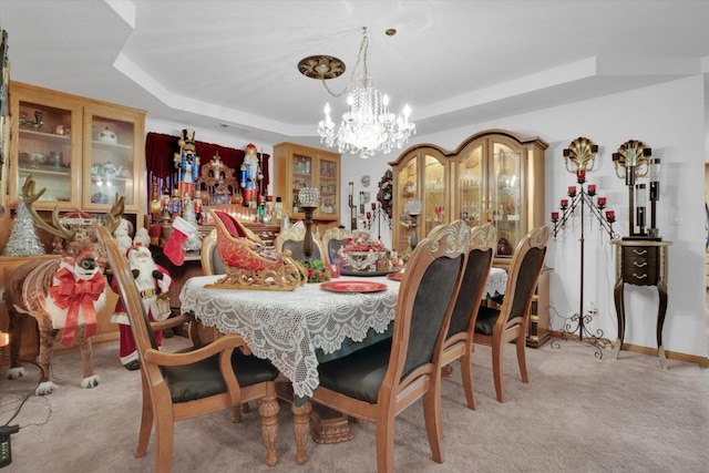 dining space featuring a raised ceiling, light colored carpet, and a notable chandelier