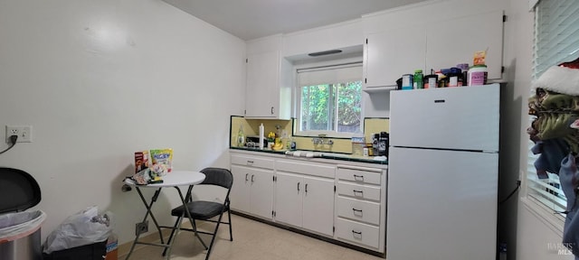 kitchen featuring white cabinets, sink, and white fridge