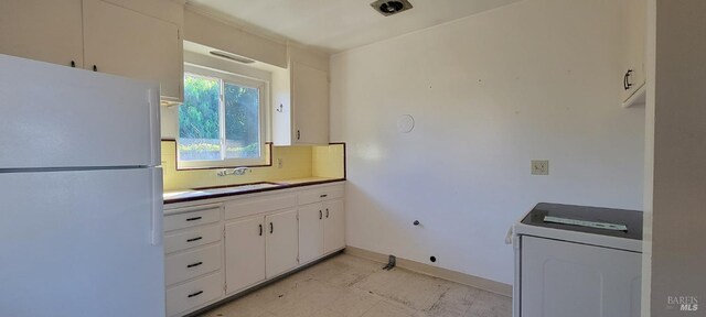 kitchen featuring white fridge, washer / dryer, white cabinetry, and sink