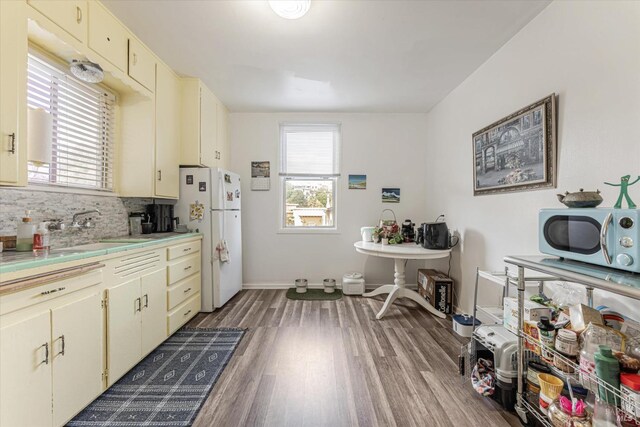 kitchen with cream cabinetry, wood-type flooring, white fridge, and tasteful backsplash