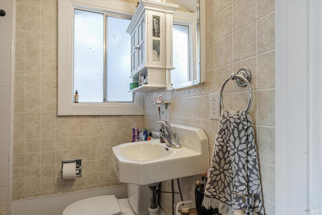 bathroom featuring plenty of natural light, toilet, and tile walls