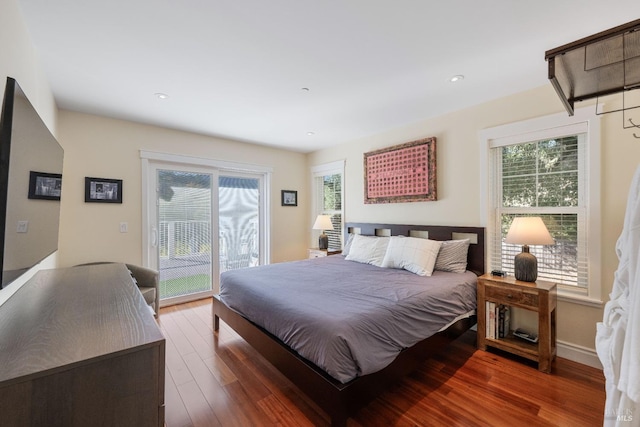 bedroom featuring dark hardwood / wood-style flooring, access to outside, and multiple windows