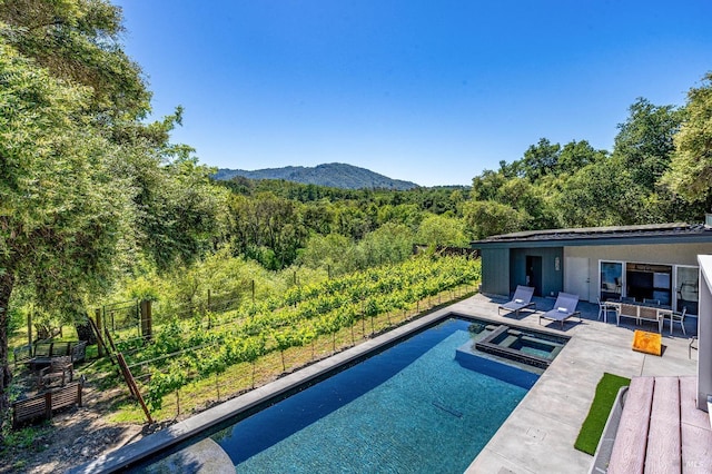 view of swimming pool featuring a mountain view, a patio, and an in ground hot tub