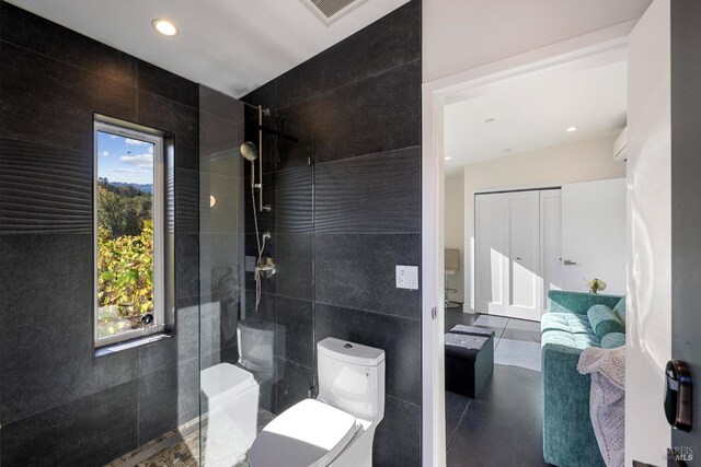 bathroom featuring a healthy amount of sunlight, tile walls, and toilet