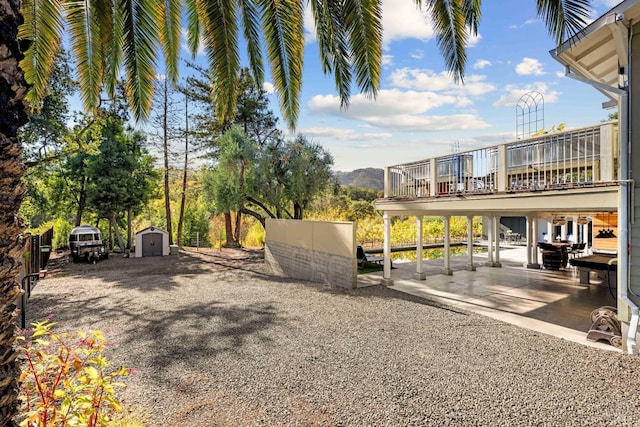 view of yard with a patio area, a mountain view, a balcony, and a storage shed