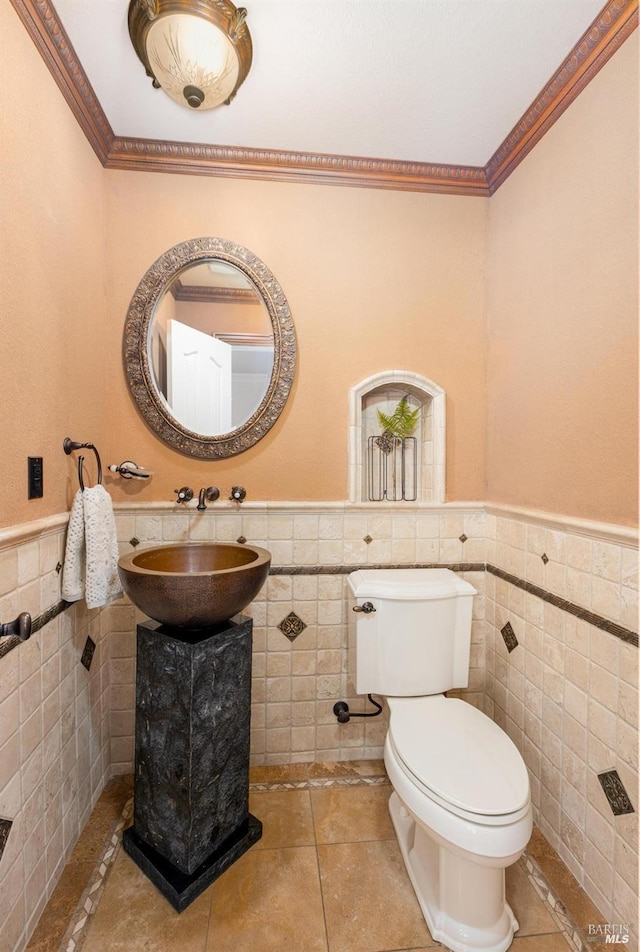 bathroom featuring tile patterned floors, crown molding, tile walls, and toilet