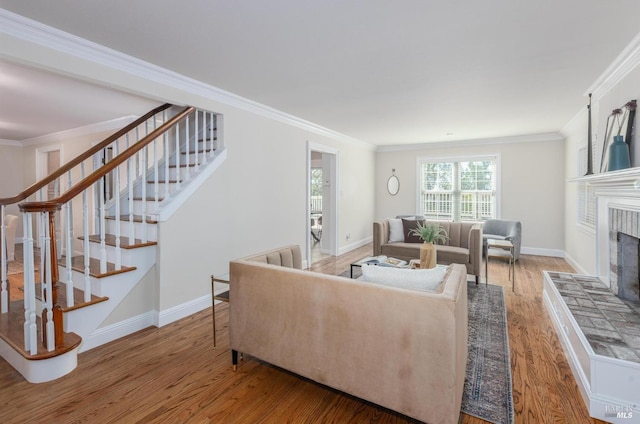 living room featuring hardwood / wood-style floors, ornamental molding, and a tile fireplace