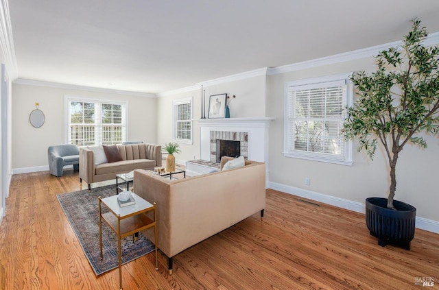 living room with crown molding, a fireplace, and light wood-type flooring