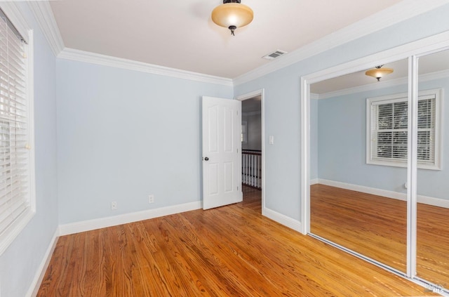 unfurnished bedroom featuring a closet, ornamental molding, and hardwood / wood-style flooring