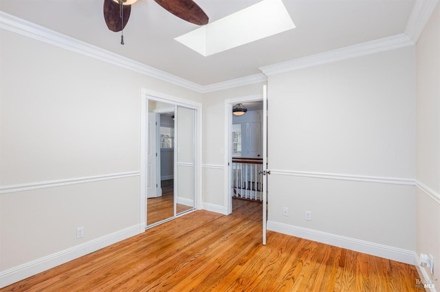 unfurnished room featuring a skylight, crown molding, light hardwood / wood-style flooring, and ceiling fan