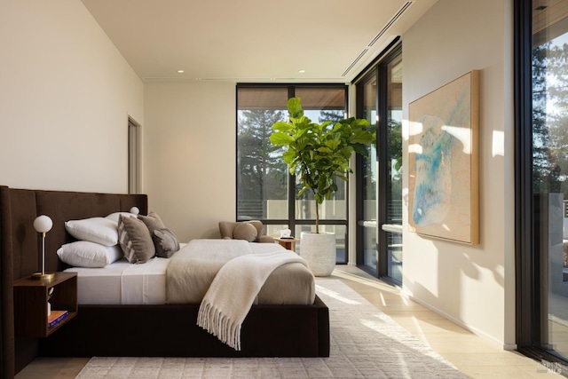 bedroom with a wall of windows and wood finished floors