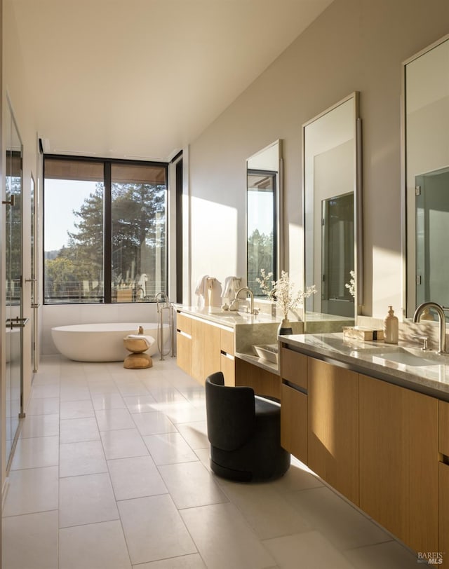 bathroom featuring tile patterned flooring, a freestanding tub, and vanity