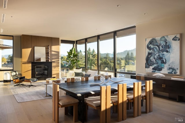 dining area featuring light wood-type flooring, expansive windows, visible vents, and a fireplace