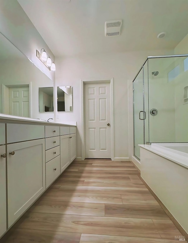 bathroom with a shower with door, vanity, and wood-type flooring