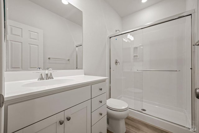 bathroom with vanity, hardwood / wood-style flooring, toilet, and a shower with shower door