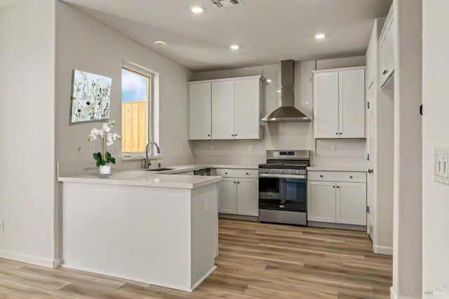 kitchen featuring white cabinetry, stainless steel range, wall chimney exhaust hood, and light wood-type flooring