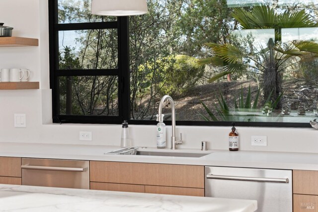 kitchen with light stone counters, hanging light fixtures, exhaust hood, and stainless steel range with gas stovetop