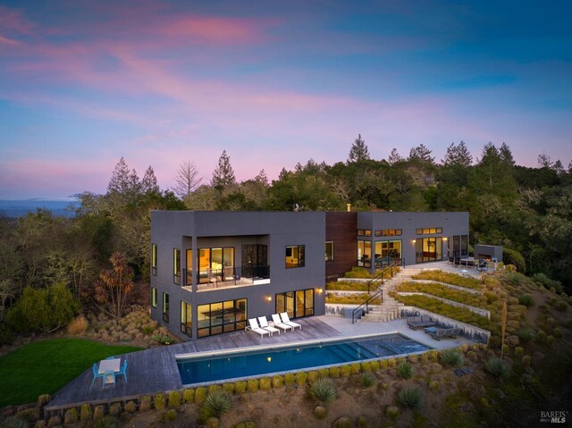 patio terrace at dusk featuring an outdoor fireplace and grilling area