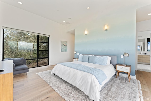 bedroom with connected bathroom and light hardwood / wood-style flooring