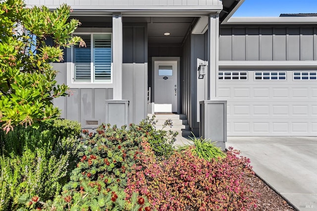 view of exterior entry featuring a garage, concrete driveway, and board and batten siding