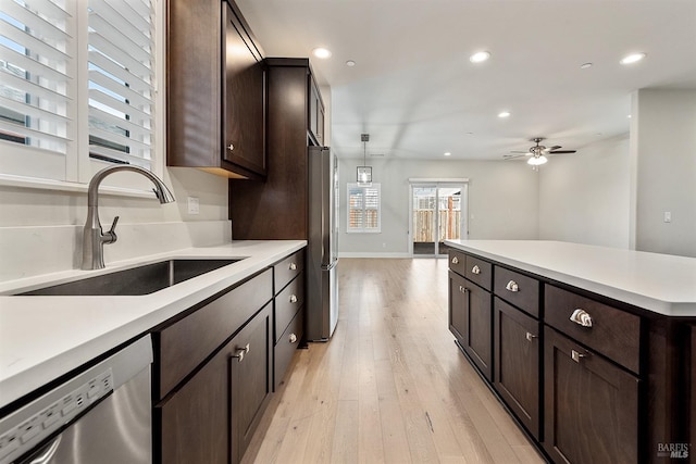 kitchen with light wood finished floors, recessed lighting, appliances with stainless steel finishes, a sink, and dark brown cabinets