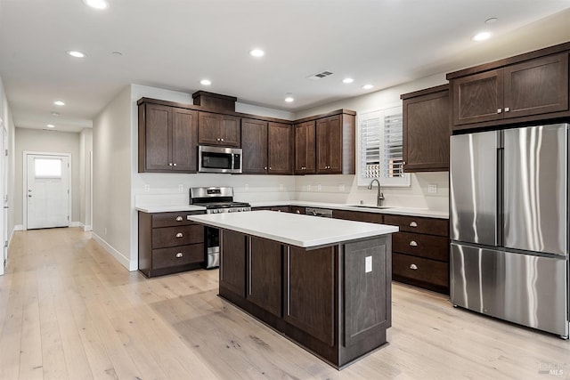 kitchen featuring stainless steel appliances, visible vents, a sink, dark brown cabinetry, and light wood-type flooring